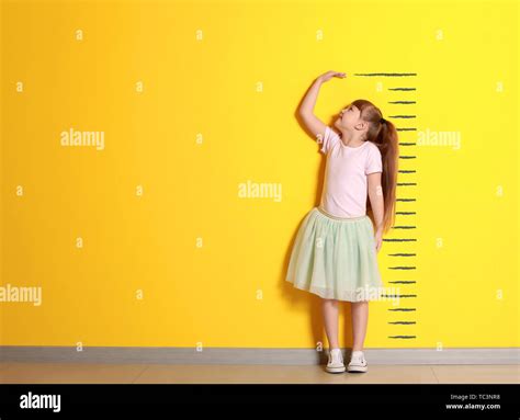 Cute Little Girl Measuring Height Near Color Wall Stock Photo Alamy