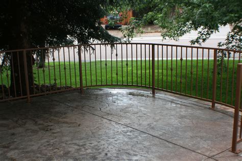 Patio With Colored Stamped Concrete And Rod Iron Railing In Old Farm