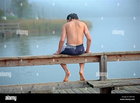 Kleiner Junge In Der Badehose Sitzt Auf Einem Zaun An Einem See Stockfotografie Alamy