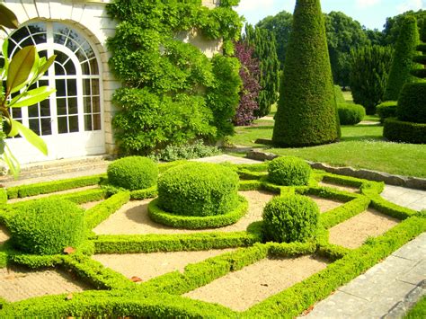 An Outdoor Garden With Hedges And Trees In The Center Surrounded By