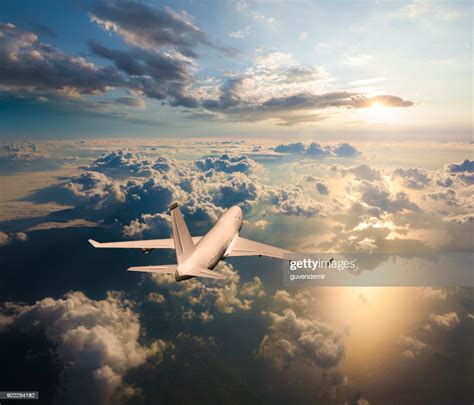 Passenger Airplane Flying Above Clouds During Sunset High Res Stock