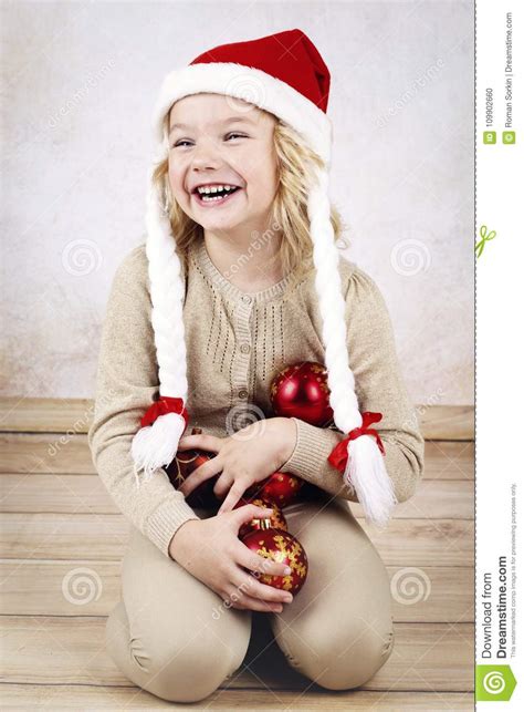 Laughing Little Girl Wearing Christmas Hat And Holding Christmas Balls