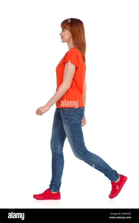 Walking Young Woman In Orange T Shirt Jeans And Red Sneakers Side