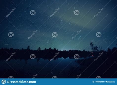 Long Exposure Night Shot Featuring Star Trails Lake Reflection And A