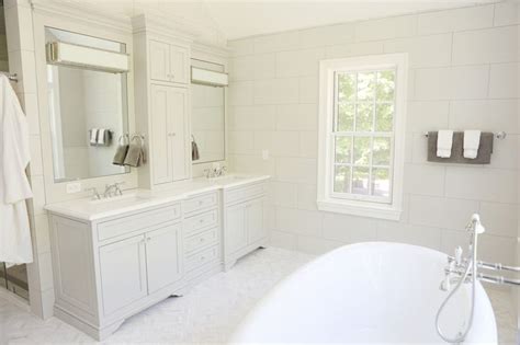 A Large White Bathtub Sitting Next To Two Sinks In A Bathroom Under A