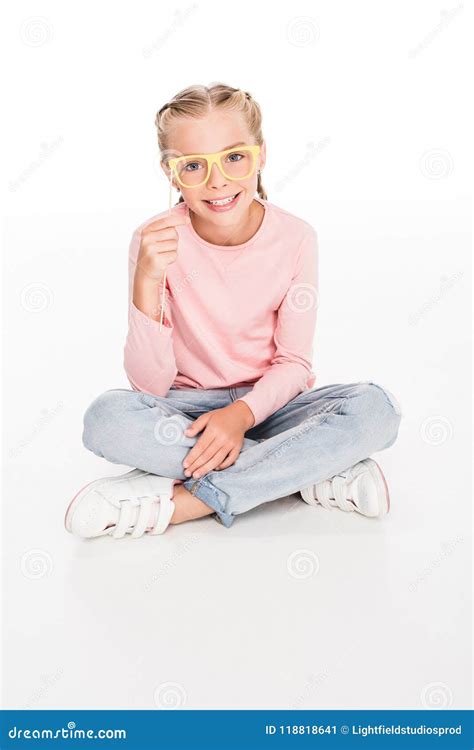 Cheerful Child Sitting On Floor With Legs Crossed And Playing With