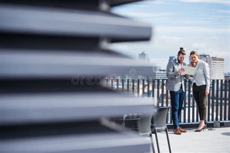 Two Young Business People With Tablet Standing On A Terrace Outside