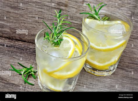 Detox Water Flavored With Sliced Lemon And Rosemary On A Rustic Wood