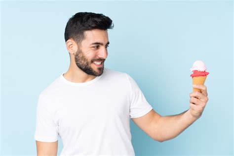 Hombre caucásico con un helado de cucurucho aislado en la pared azul