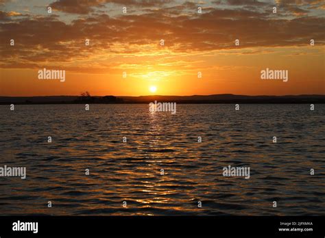 A Scenic View Of The Shiny Sea Under The Orange Sunset Sky Stock Photo