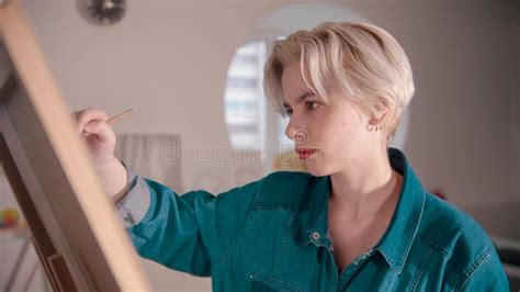 A Young Blonde Attractive Woman Artist Draws A Painting Stock Image