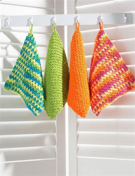 Three Colorful Crocheted Towels Hanging On A White Rack In Front Of