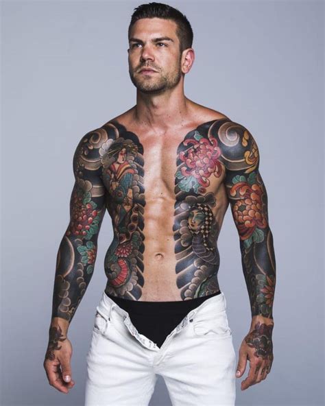 A Man With Many Tattoos On His Chest And Arms Is Posing For The Camera While Wearing White Shorts