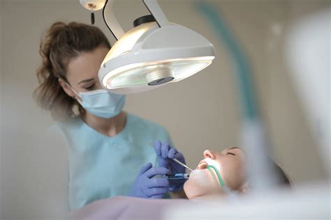 Serious Female Dentist Treating Teeth Of Patient In Modern Clinic