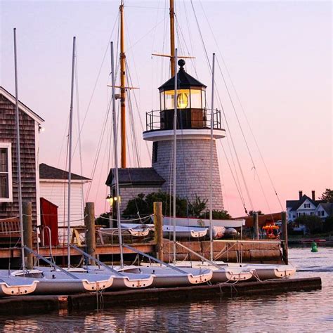 Several Sailboats Are Docked In Front Of A Light House