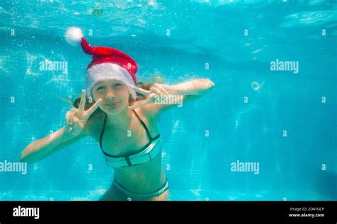 Happy Girl Pose Underwater Wearing Santa Claus Hat In The Pool Diving