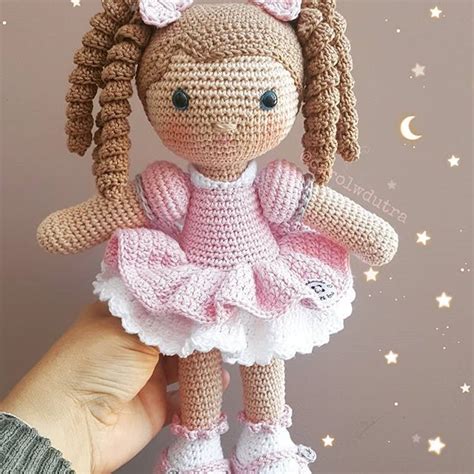 A Crocheted Doll In A Pink Dress Is Held Up By Someone S Hand