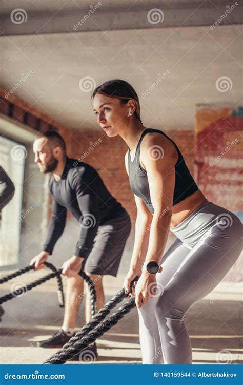 Woman And Man In Gym Functional Training With Battle Rope Exercising