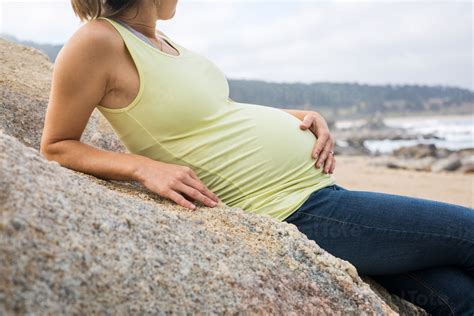 Pregnant Woman Sitting On A Rock Stock Photo PixelTote