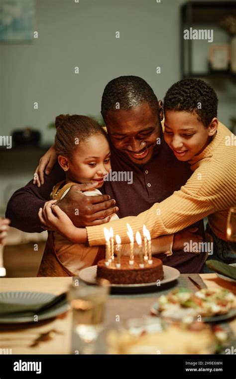 Vertical Portrait Of Happy African American Man Embracing Children