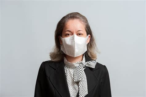 Side View Of Middle Aged Mixed Race Woman In Formal Wear Wearing White Surgical Mask For