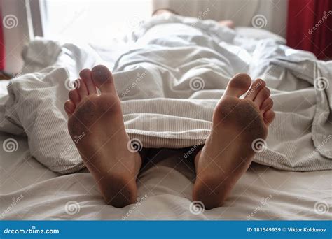 Dirty Bare Feet Of A Sleeping Person Showing Out Of The Blanket Stock