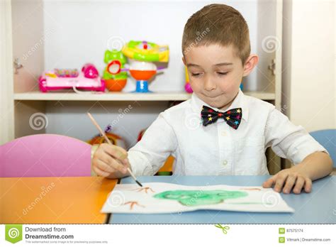 Adorable Child Boy Draws A Brush And Paints In Nursery Room Kid In
