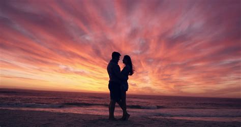 happy couple kissing on beach at sunset silhouette in love dating on honeymoon red dragon stock