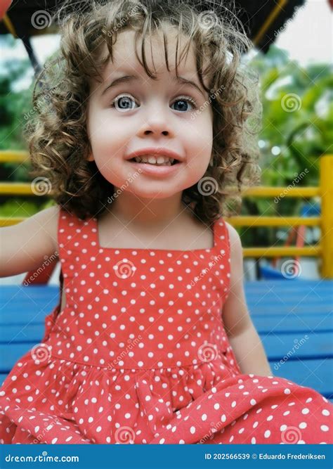 Little Girl Playing On The Playground Looking And Laughing At Camera