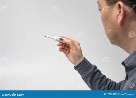 A Male Hand Holding A Digital Thermometer In Hand On A White Background