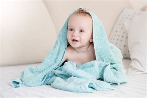 Happy Cheerful Baby Boy Sitting On Bed Under Blanket Stock Photo