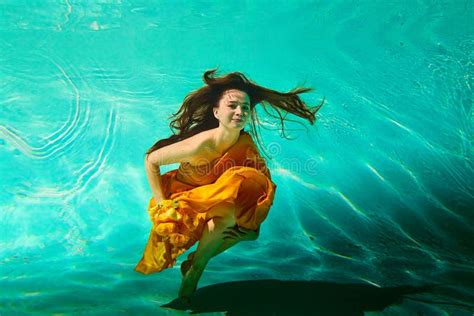 girl in a beautiful dress under blue water female model posing under water in swimming pool