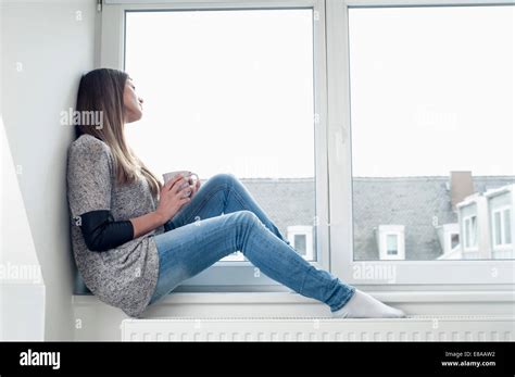 Young Woman Sitting On Window Sill At Home Stock Photo Alamy