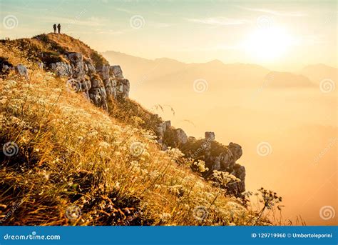 Hikers Walking At Sunrise On Top Of Italian Alps Mountains Stock Photo