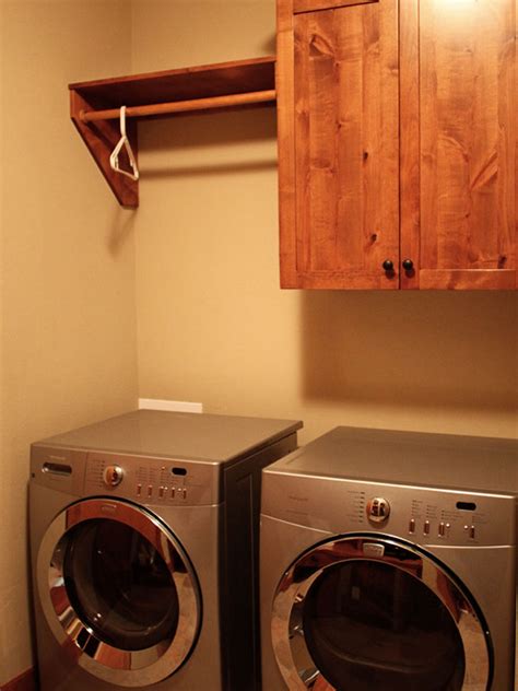 Laundry area with white cabinets, washer and dryer, clothes hanging on rack on built in shelf, storage compartments, and wicker laundry basket on floor. Shelf with Hanging Rod: Extend Your Storage - HomesFeed