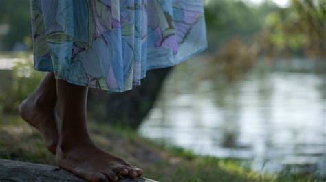 Slim African American Female Feet Walking On Tree Trunk On River Bank