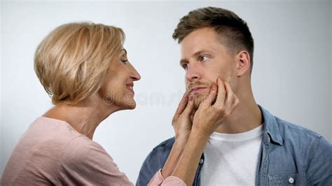 Mother Pinching Cheeks To Infantile Adult Son Under Mom Overprotection