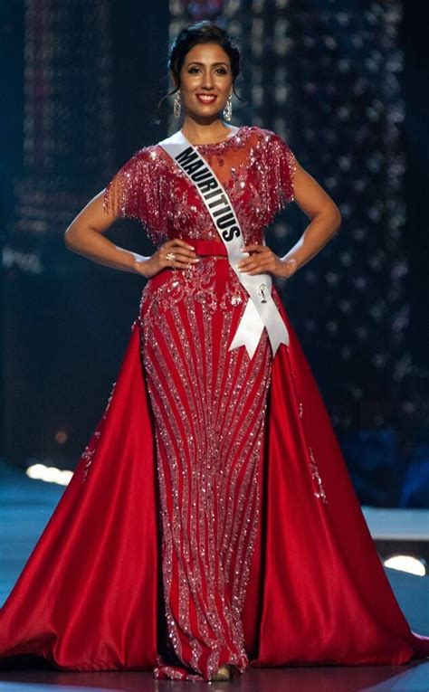 A Woman In A Red Gown Standing On A Stage With Her Hands On Her Hips