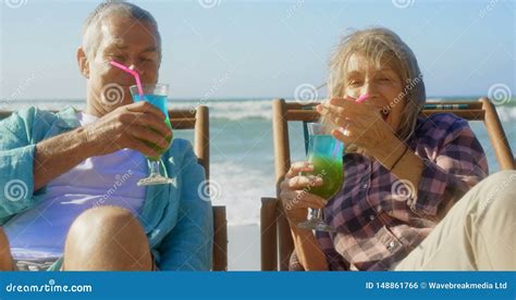 Front View Of Active Senior Caucasian Couple Toasting Glasses Of Cocktail On The Beach 4k Stock