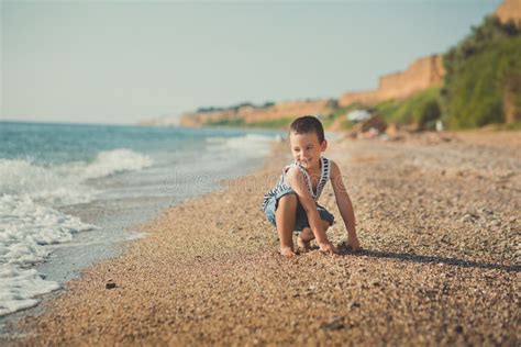 Un Muchacho Se Sienta En La Playa En Una Camisa Rayada Con Un Salvavidas Marino Liferound Un