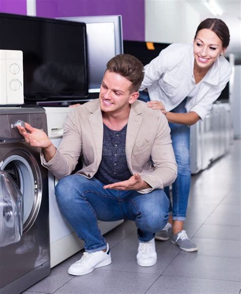 Pareja Joven Interesada Eligiendo Lavadora En Hipermercado Imagen De