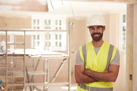 Portrait Of Smiling Male Builder Wearing Hard Hat Working In New Build