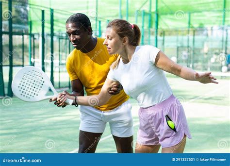 African American Man Instructor Teaches A Young Woman To Play Padel