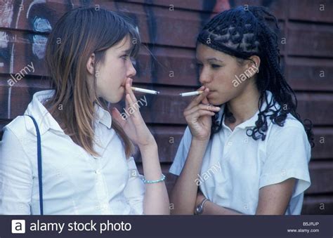 Download This Stock Image Two Secondary School Girls Smoking Hiding