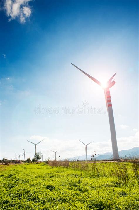 Wind Turbine On The Green Grass Over The Blue Clouded Sky Wind