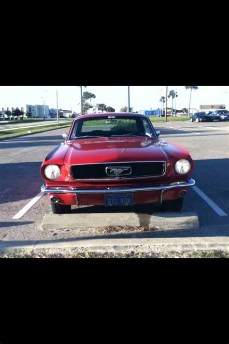 An Old Red Mustang Parked In A Parking Lot