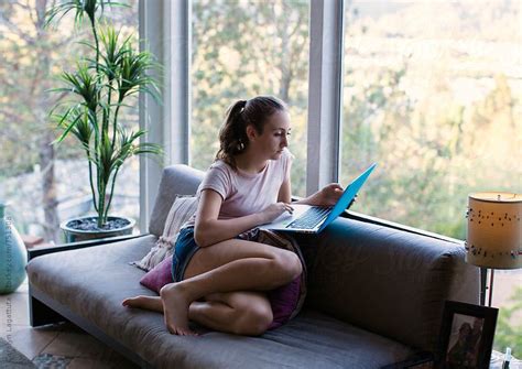 Teenage Girl On The Couch In A Modern Home Looking At The Laptop By