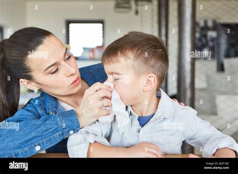 Caring Mother Blowing Her Son Nose With Cold Or Runny Nose At Home