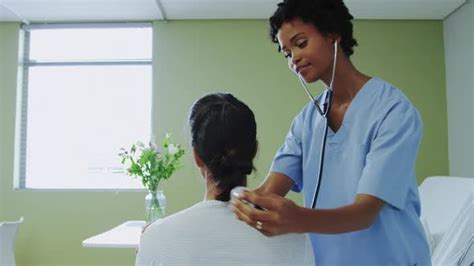 Side View Of African American Female Doctor Examining Female Patient In