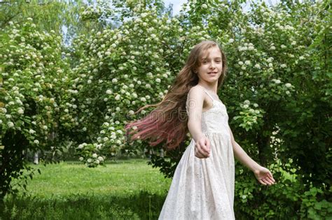 beautiful white girl 11 years old with long hair standing near a birch tree on a sunny summer